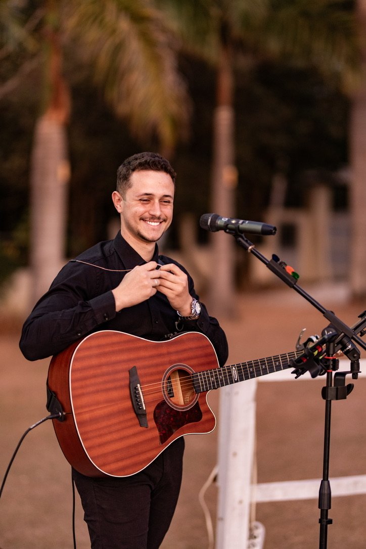 Henrique Alencar sorrindo com violão